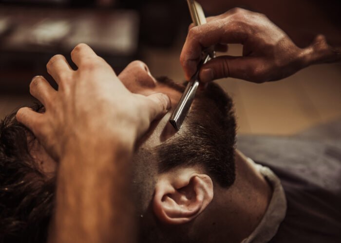 Men barber shaves his beard.