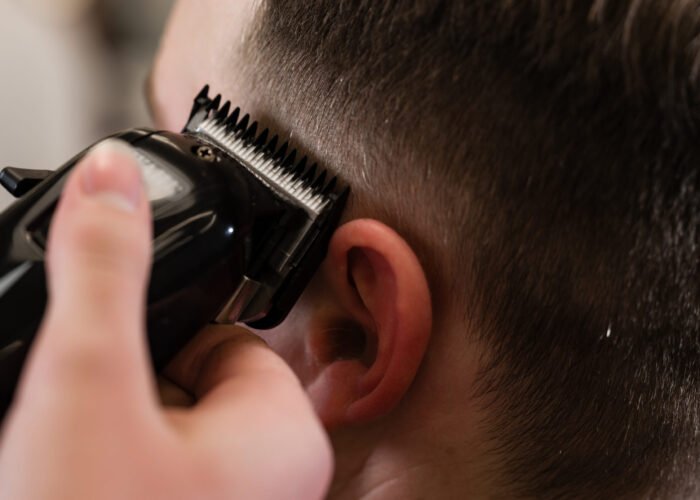 Haircut and alignment of the head contour with a hair clipper and trimmer. Short haircut in the barbershop.